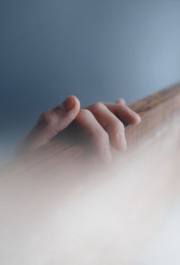 Close-up of human hand  on wood board in fog