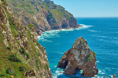 Scenic view of rocks in sea against blue sky