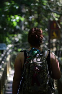 Rear view of woman with backpack hiking in forest