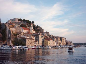 Boats in sea in front of town against sky