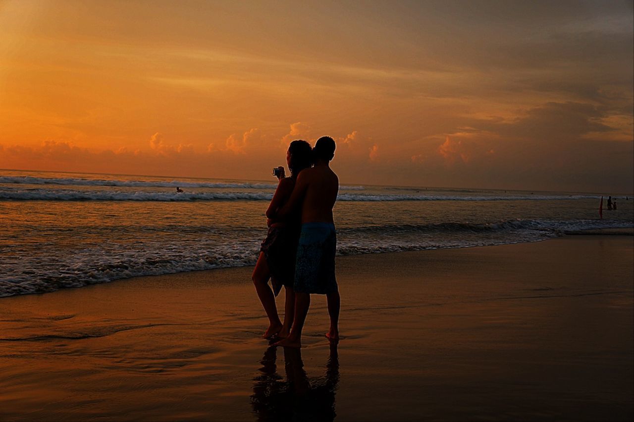 sunset, sea, beach, horizon over water, water, shore, sky, silhouette, orange color, lifestyles, standing, leisure activity, scenics, beauty in nature, tranquil scene, full length, tranquility, men