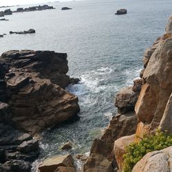 Scenic view of sea by cliff against sky