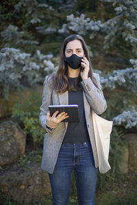 Full length of young woman using mobile phone in winter