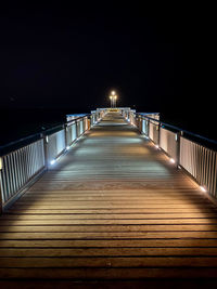 Empty footbridge against clear sky at night