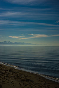 Black volcanic sand beach and caucasus mountains with snow peaks in winter time