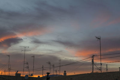 Silhouette electricity pylon against sky during sunset