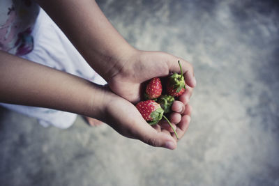 High angle view of hand holding strawberries