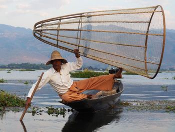 Man holding boat in sea against sky