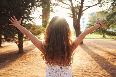 Rear view of young woman standing by tree