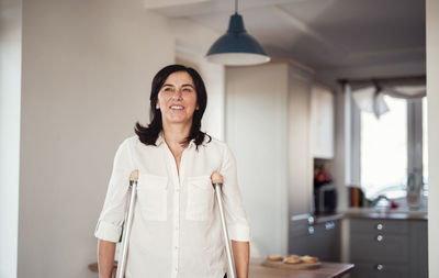 Mature woman with crutches, alone at home