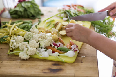 Girl cutting vegetables in kitchen, sweden