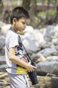 Boy with camera standing on rock