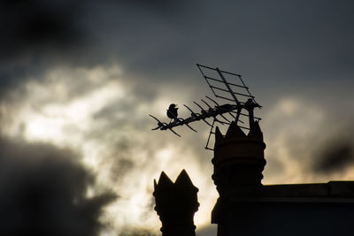 Low angle view of weather vane at sunset