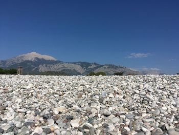 Surface level of stones on land against blue sky