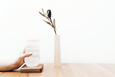 Cropped image of woman hand holding water glass on table against white background