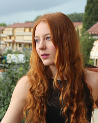 Portrait of beautiful woman with long red hair and blue eyes looking away 