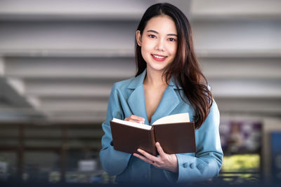 Portrait of young woman holding diary