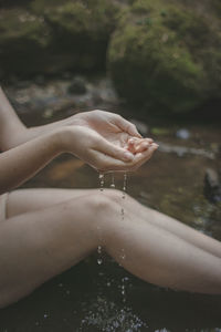 Midsection of woman sitting at lakeshore