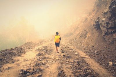 Rear view of woman walking on road against sky