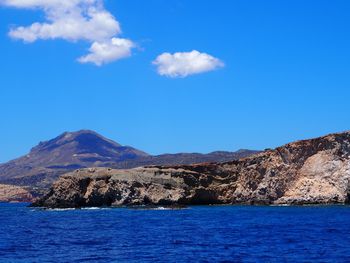 Scenic view of sea and mountains against blue sky