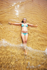 Rear view of woman in bikini standing in water