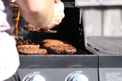 Arm of man preparing food on barbecue 