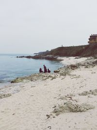 People on beach against clear sky