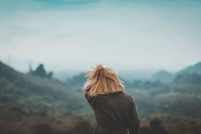 Rear view of woman standing on mountain against sky