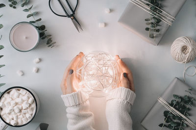 Cropped hands of woman holding string lights in container on table