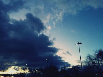 Low angle view of silhouette trees against dramatic sky