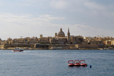 Boat sailing in sea against sky in city