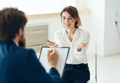 Young woman using mobile phone while sitting at clinic