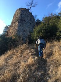 Low angle view of man hiking towards old ruin on hill