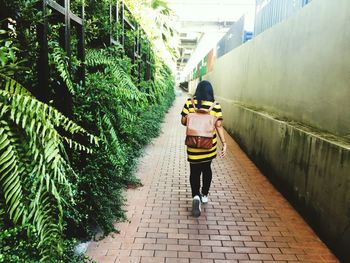 Rear view of woman walking on footpath