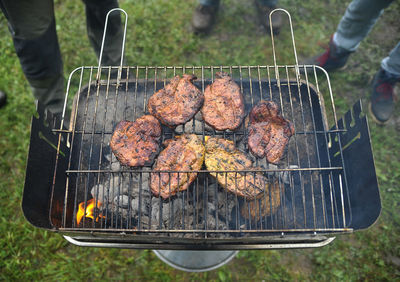 High angle view of meat cooking on barbecue grill at yard