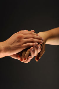 Close-up of hand holding hands over black background