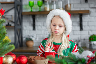 Cute little child girl eating sweet cookies and drinking hot cocoa