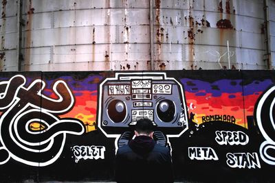 Woman standing by graffiti wall