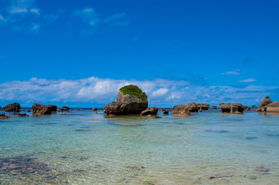 Rocks on beach against blue sky