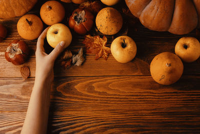 Cropped hand of woman holding apple on table