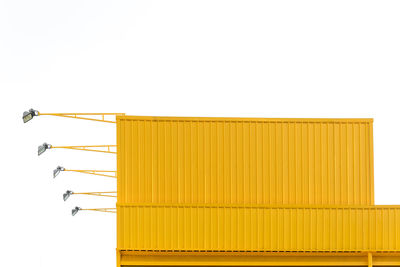 Close-up of yellow built structure with lighting equipment against clear sky