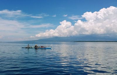 Men sitting in boat on sea against blue sky during sunny day