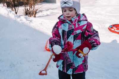 Happy and cheerful child in winter, in snowy weather, makes snowballs out of snow. hello winter