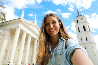 Portrait of smiling young woman standing against building