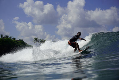 Man surfing in sea against sky