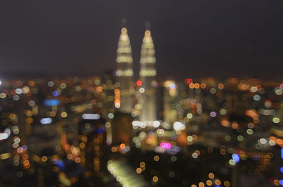 Defocused image of illuminated cityscape against sky at night