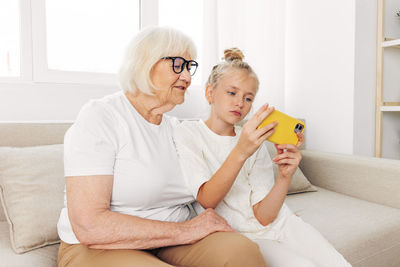 Portrait of young woman using phone while sitting on sofa at home