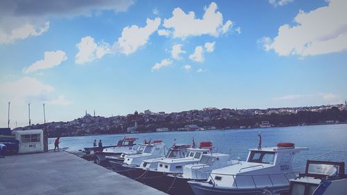 Boats moored at harbor against sky