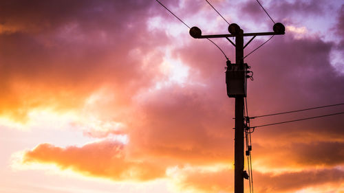 Low angle view of telephone pole against sky during sunset