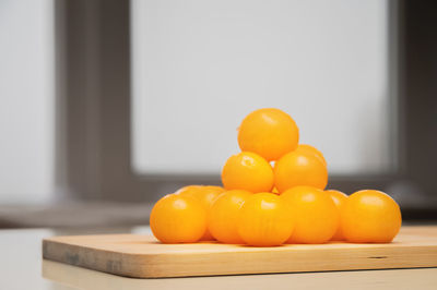 A heap of yellow cherry tomatoes on a wooden cutting board in the kitchen on a white table